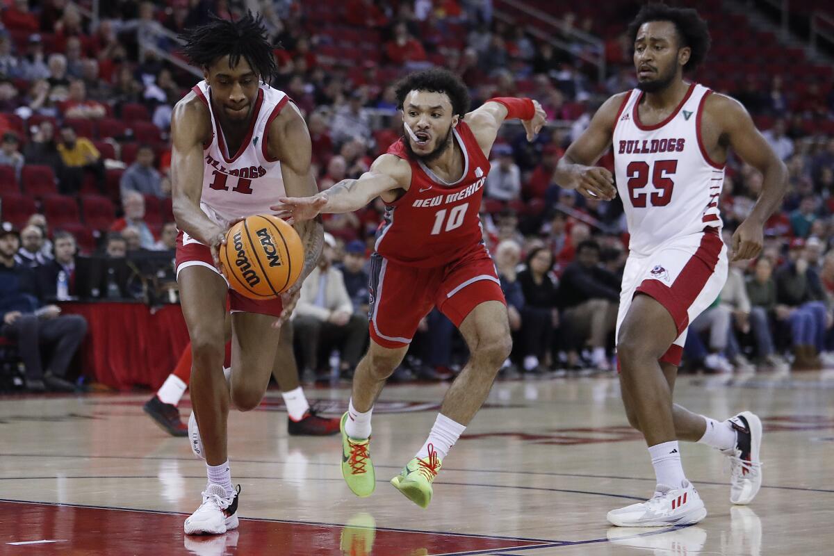 New Mexico's Jaelen House and Fresno State's Isaih Moore, left, reach for the ball as Fresno State's Anthony Holland watches during the second half of an NCAA college basketball game in Fresno, Calif., Tuesday, Jan. 3, 2023. (AP Photo/Gary Kazanjian)