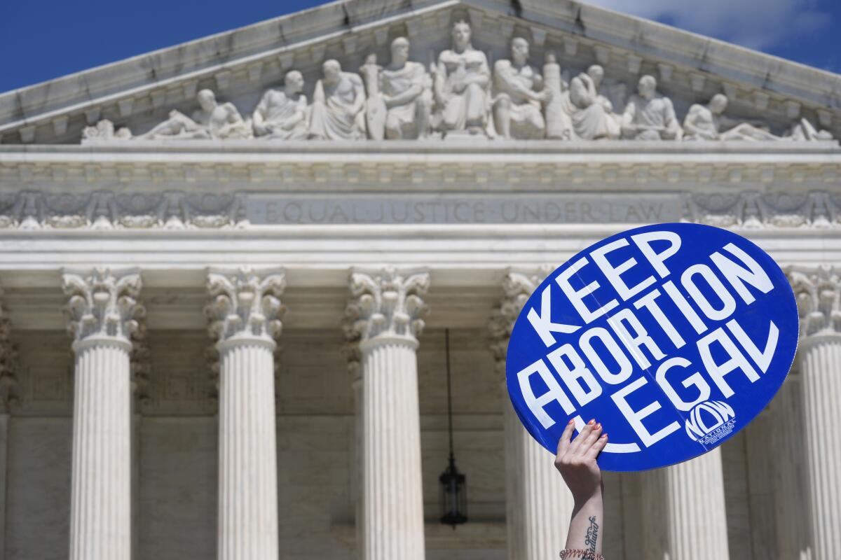 A person holds up a  "Keep Abortion Legal" sign in front of the Supreme Court building.
