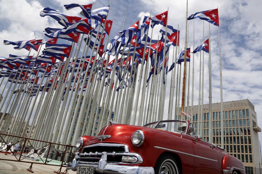 FILE - A classic American convertible car passes beside the United States embassy as Cuban flags fly at the Anti-Imperialist Tribune, a massive stage on the Malecon seaside promenade in Havana, Cuba, July 26, 2015. The United States Embassy in Cuba is opening visa and consular services on Wednesday, Jan 4, 2023. It was the first time since a spate of unexplained health incidents among diplomatic staff in 2017 slashed American presence in Havana(AP Photo/Desmond Boylan, File)