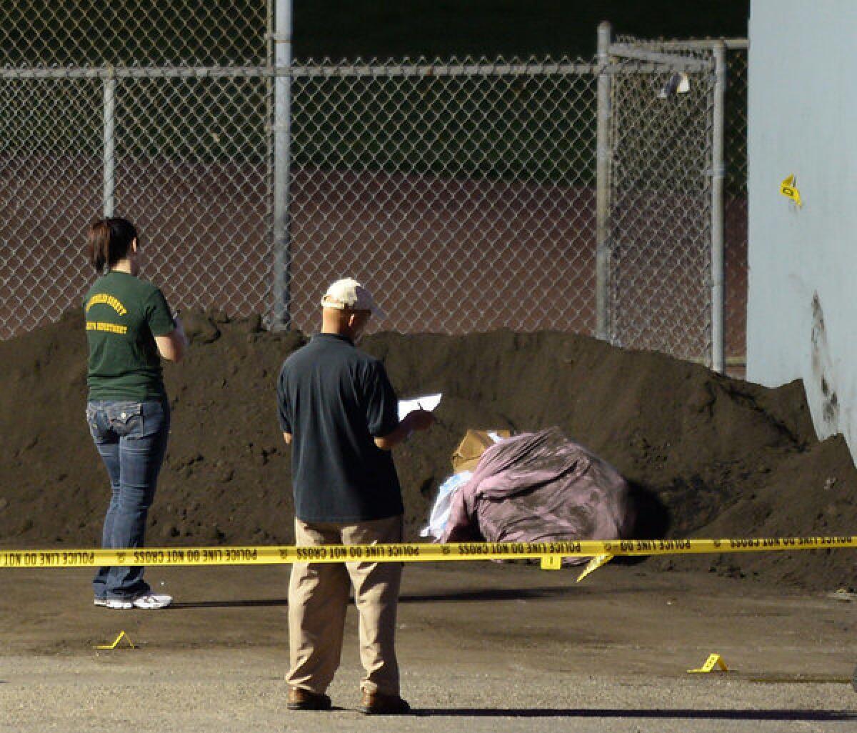 Investigators look over the scene where a body was found in a bag Thursday at a park in Manhattan Beach.