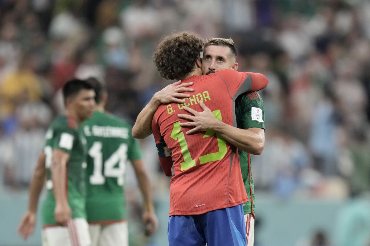 Mexico's Hector Herrera (right) hugs goalkeeper Memo Ochoa after the team's World Cup loss November 26, 2022.