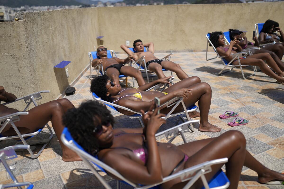 Varias personas descansan en busca de obtener unas líneas definidas de bronceado en bikinis