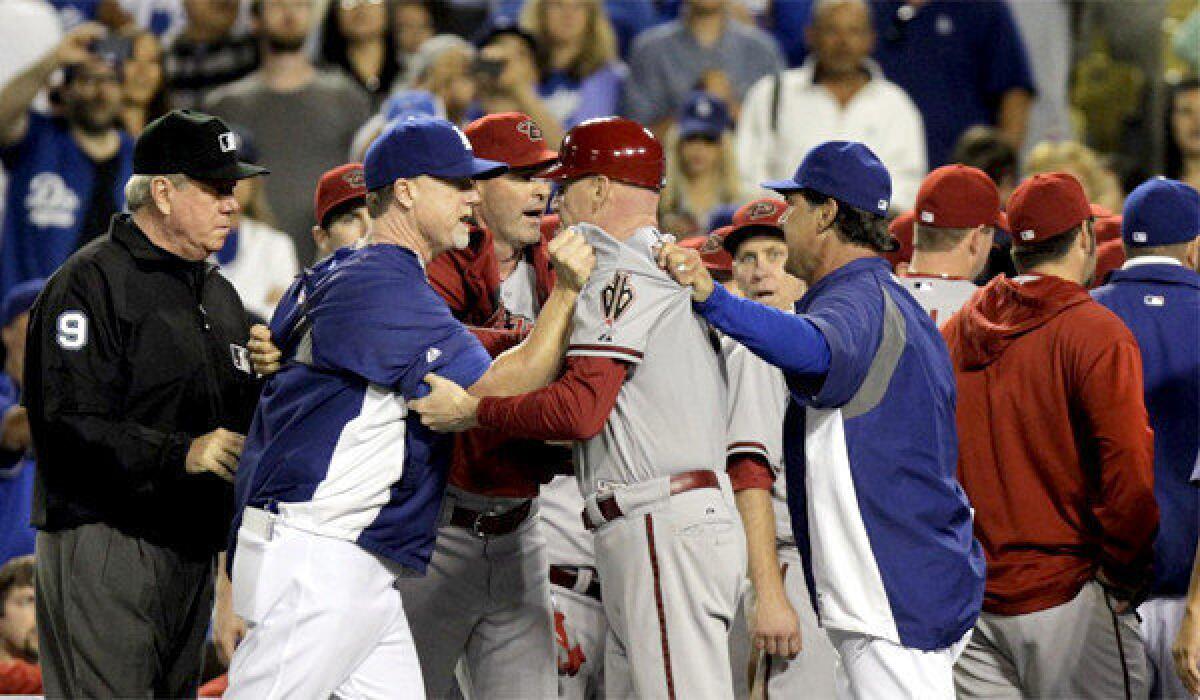 Diamondbacks third base coach Matt Williams, center, is grabbed by Dodgers hitting coach Mark McGwire, left, and L.A. Manager Don Mattingly, right, during a bench clearing brawl on Tuesday.