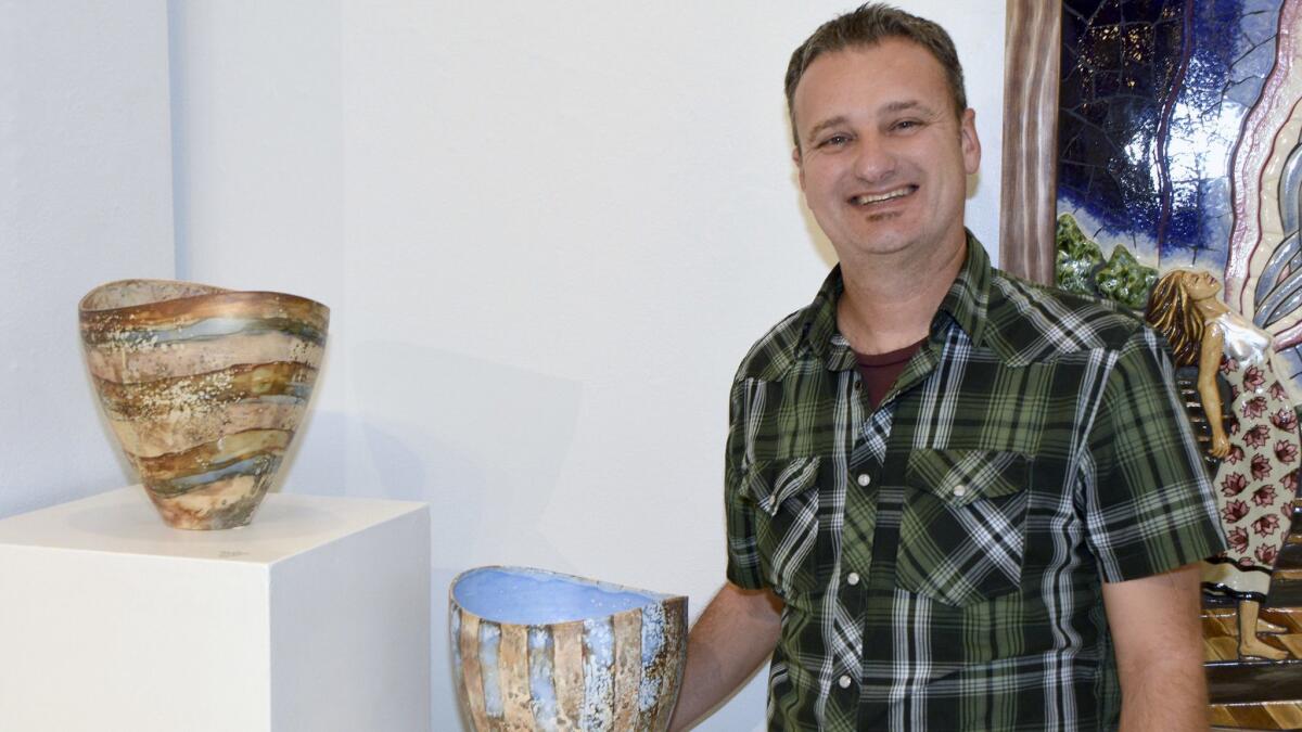 French artist Pierre Bounaud, who works in porcelain, showing off two of the 10 pieces he is currently exhibiting at the Betsy Lueke Creative Arts Center.