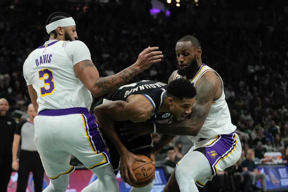 Bucks forward Giannis Antetokounmpo tries to force his way between Lakers forwards Anthony Davis and LeBron James.