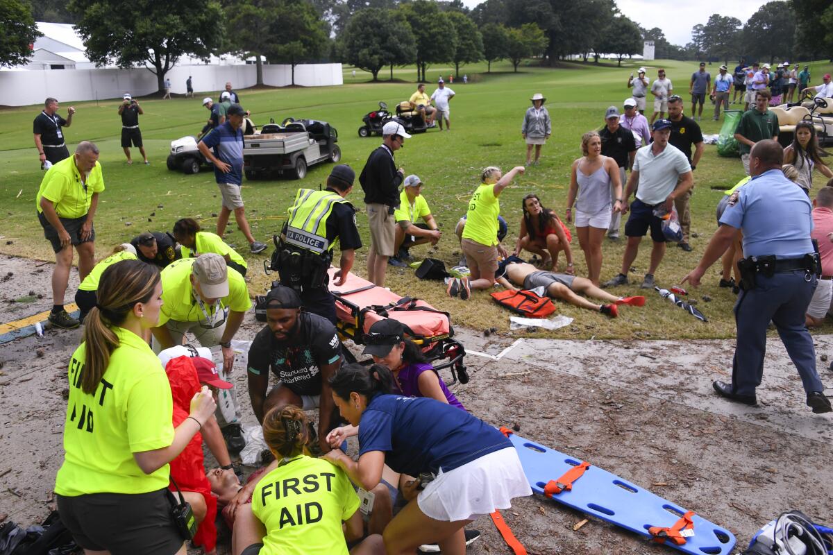 Spectators are tended to on the golf course after a lightning strike.