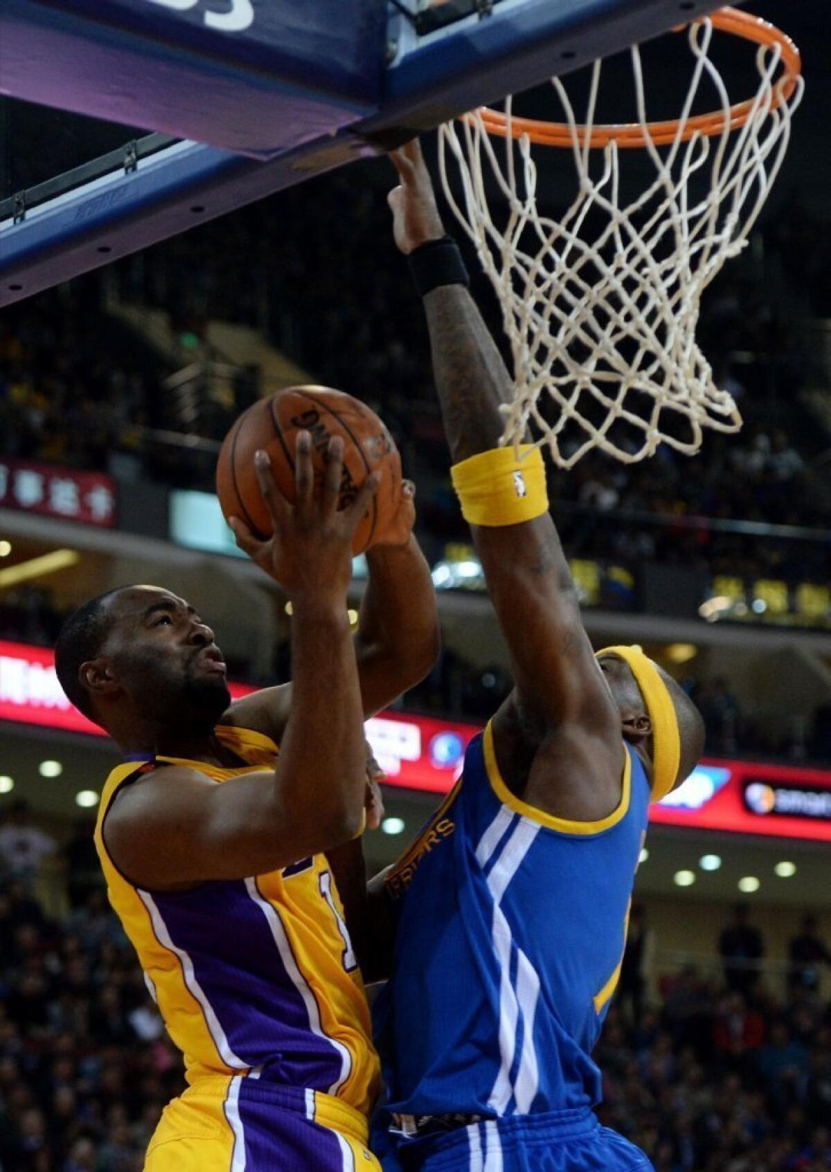 Lakers forward Marcus Landry is blocked by Golden State Warriors' Jermaine O'Neal during an exhibition game Tuesday in Beijing.