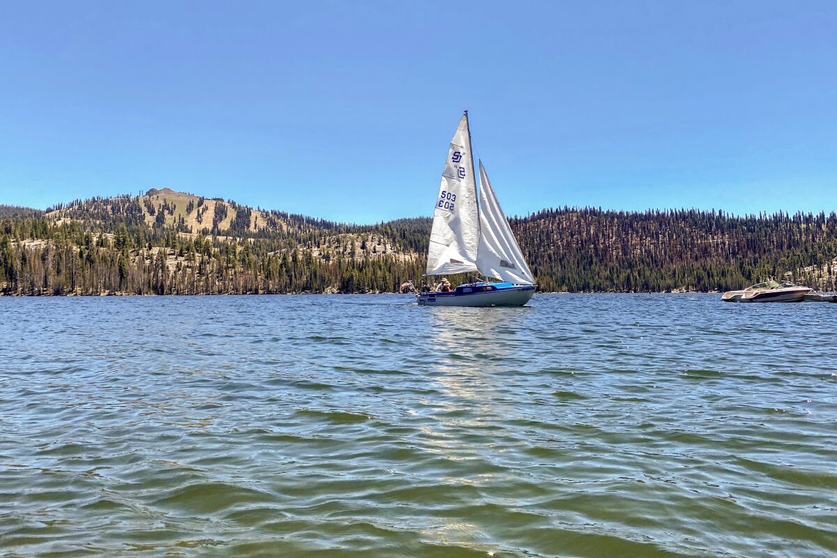 A sailboat on a lake surrounded by wooded hills