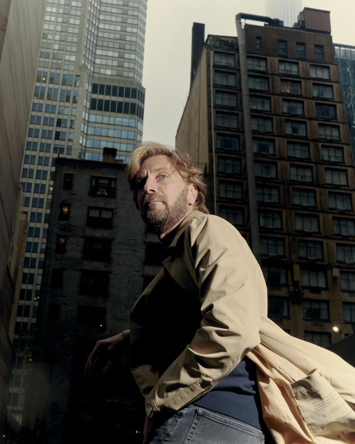 Director Ruben Ostlund stands on a balcony with New York City buildings in the background