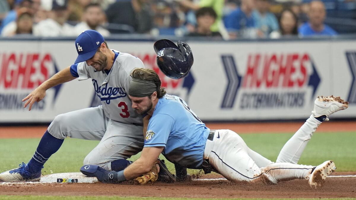 Tampa Bay's Josh Lowe loses his helmet as he beats the tag by the Dodgers' Chris Taylor to steal third base.