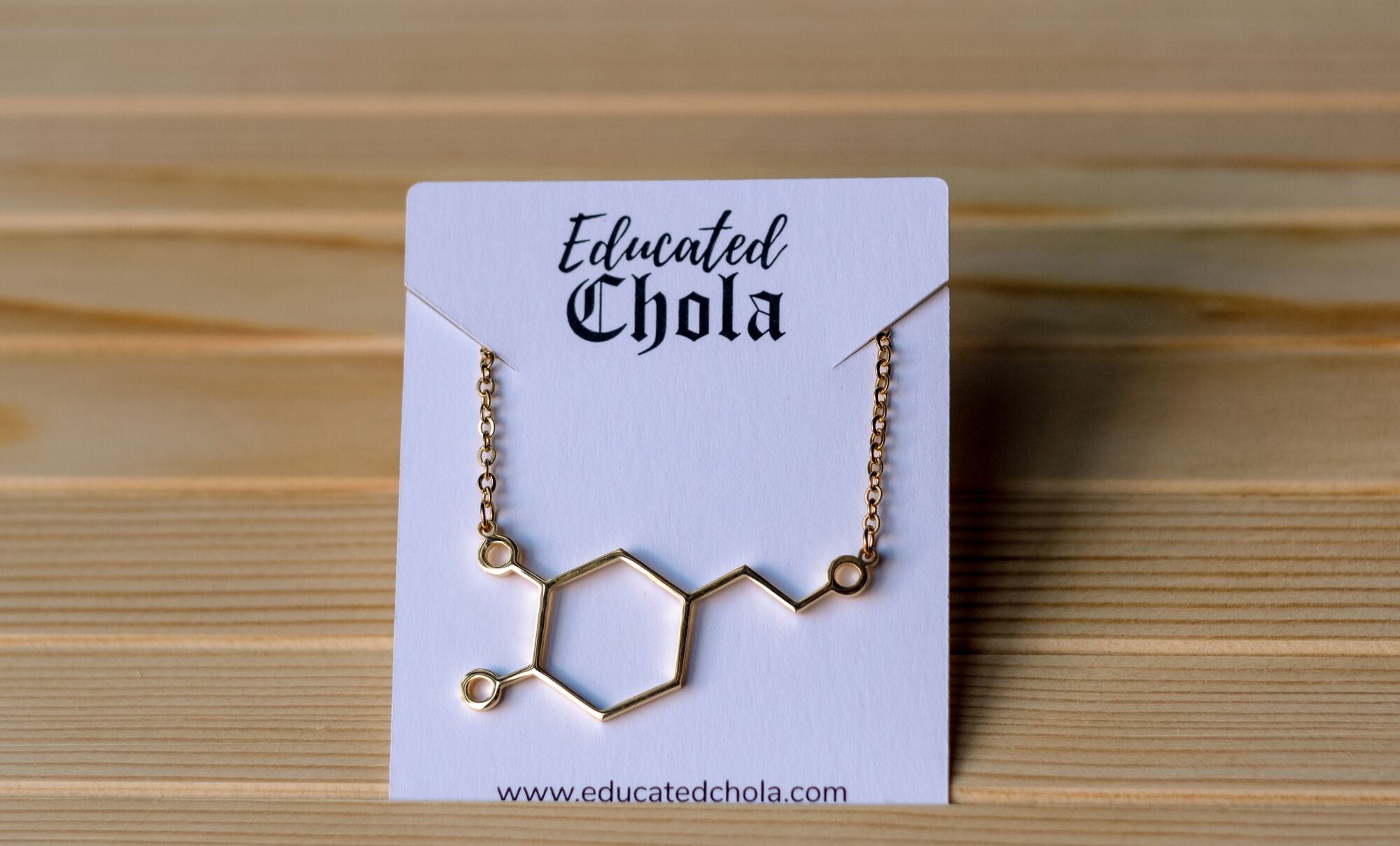 A gold Educated Chola necklace in the molecular structure of dopamine.