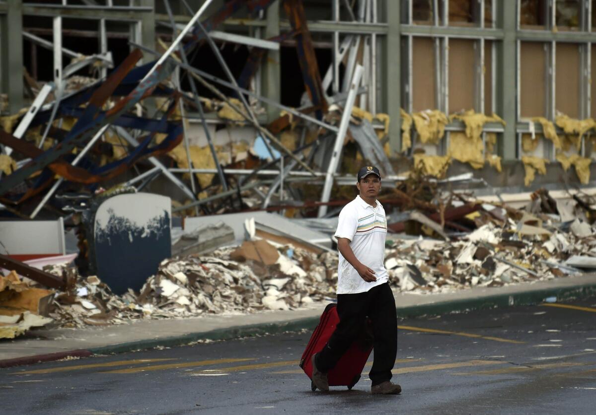 A tourist walks past Los Cabos International Airport six days after Hurricane Odile swept through on Sept. 14.