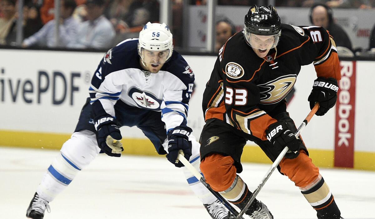 Anaheim Ducks right wing Jakob Silfverberg, right, moves the puck in front of Winnipeg Jets center on April 5.