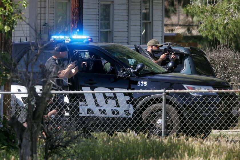 Redlands police officers train guns on a man who had taken his ex-girlfriend hostage outside an Office Depot store March 24. The woman was shot and wounded by police. The man was killed by police.