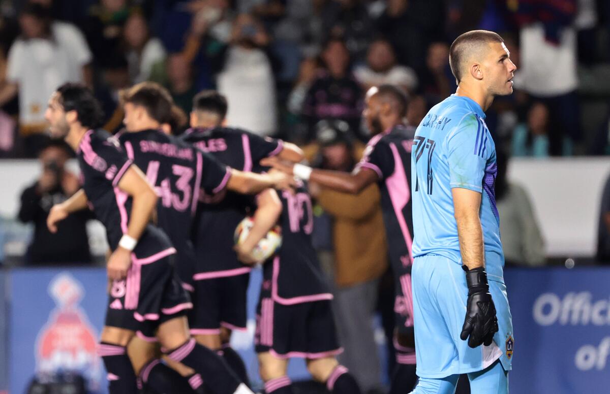 Galaxy goalie John McCarthy walks back toward the goal as Inter Miami players celebrate Lionel Messi's stoppage-time goal.