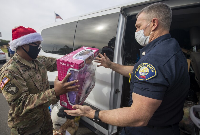 Sgt Mickey Boonyodom, left, hands a toy to Cpt. Ty Lunde,