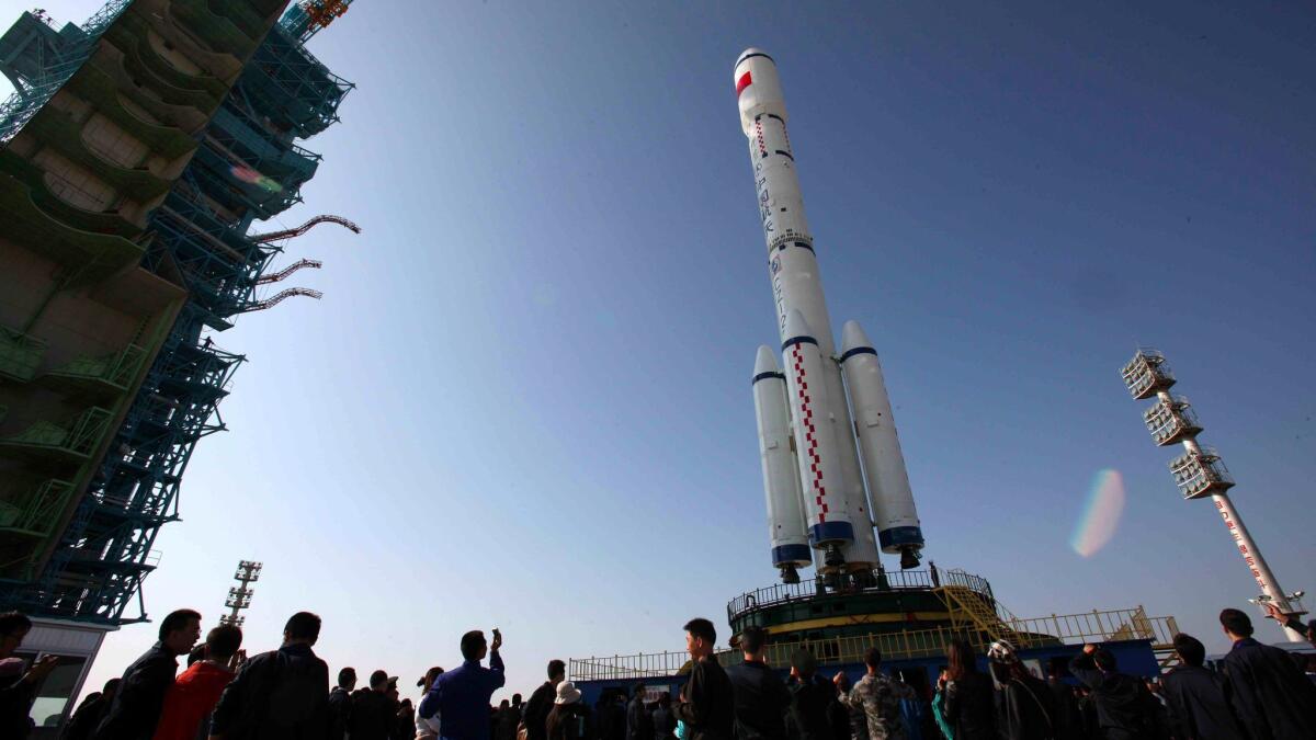 People gather to look at China's Long March 2-F rocket, which will take the Tiangong-1 space module into space, as it is rolled out onto a launch platform at the Jiuquan Satellite Launch Centre in the northwestern province of Gansu on September 20, 2011. China said it will launch its Tiangong-1 space module later September, marking its first step towards building a Chinese space station, as the Asian giant sees its space programme as a symbol of its global stature, growing technical expertise, and the Communist Party's success in turning around the fortunes of the formerly poverty-stricken nation. CHINA OUT AFP PHOTO (Photo credit should read STR/AFP/Getty Images) ORG XMIT: