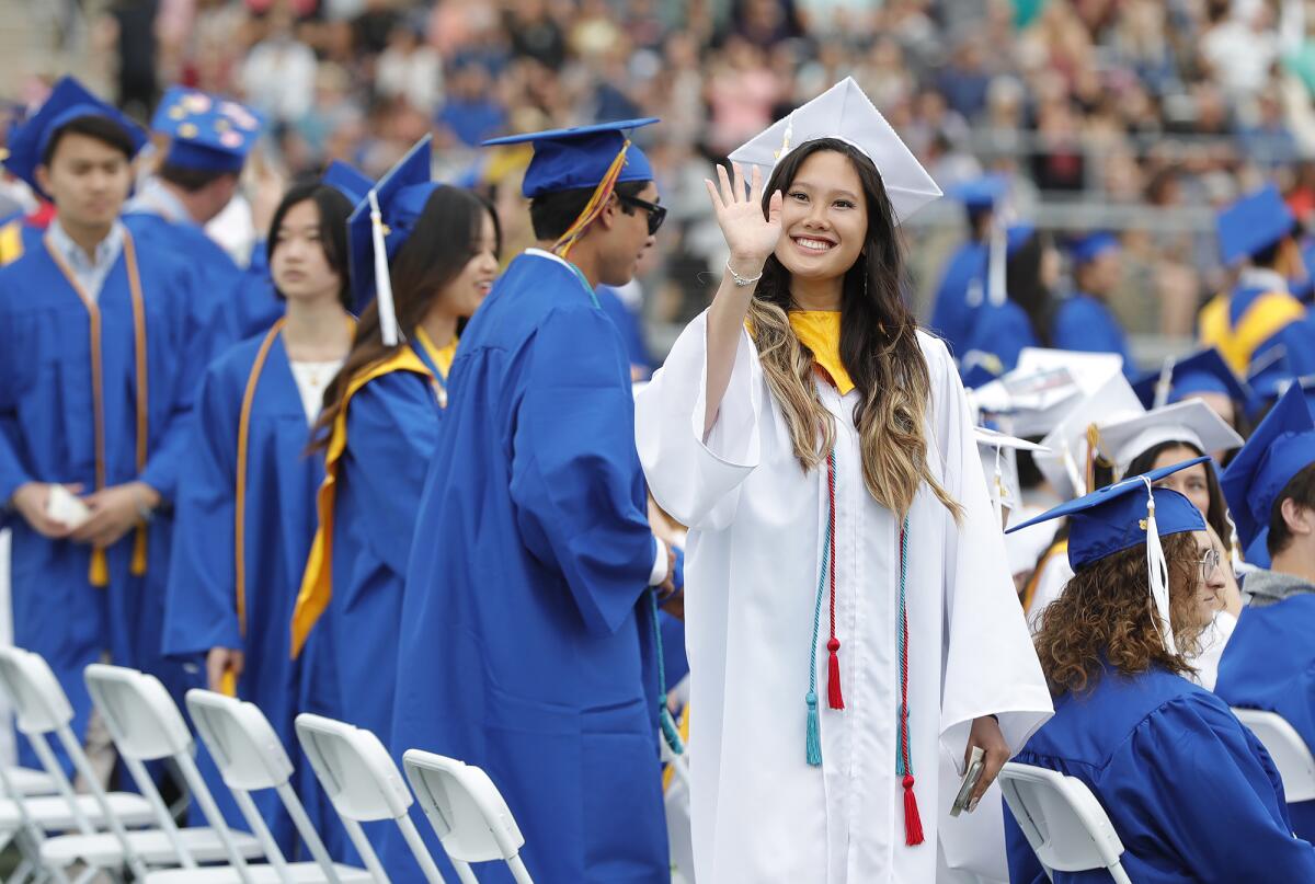 Trina Tu Nguyen waves to family as she walks into the 2023 Fountain Valley High graduation ceremony on Wednesday.