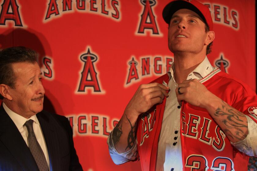 Angels owner Arte Moreno, left, watches outfielder Josh Hamilton put on his jersey during a news conference to introduce the 2010 American League MVP on Dec. 15, 2012.