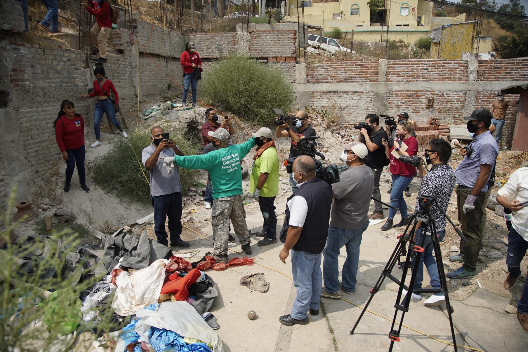 Police officers take cellphone photos of people digging for bodies inside a property.