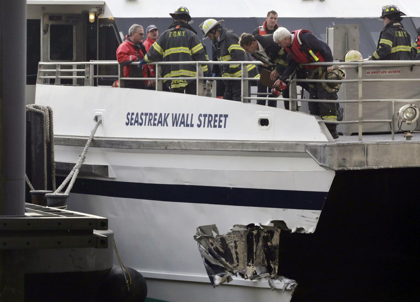 New York firefighters on the deck of the Seastreak Wall Street look at the ferry's damaged hull.