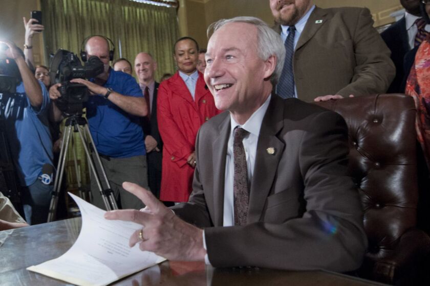 Arkansas Gov. Asa Hutchinson signs a reworked religious freedom bill into law after it passed in the House at the Arkansas state Capitol in Little Rock, Ark., Thursday, April 2, 2015. Lawmakers in Arkansas and Indiana passed legislation Thursday that they hoped would quiet the national uproar over new religious objections laws that opponents say are designed to offer a legal defense for anti-gay discrimination. (AP Photo/Brian Chilson) ORG XMIT: ARDJ110
