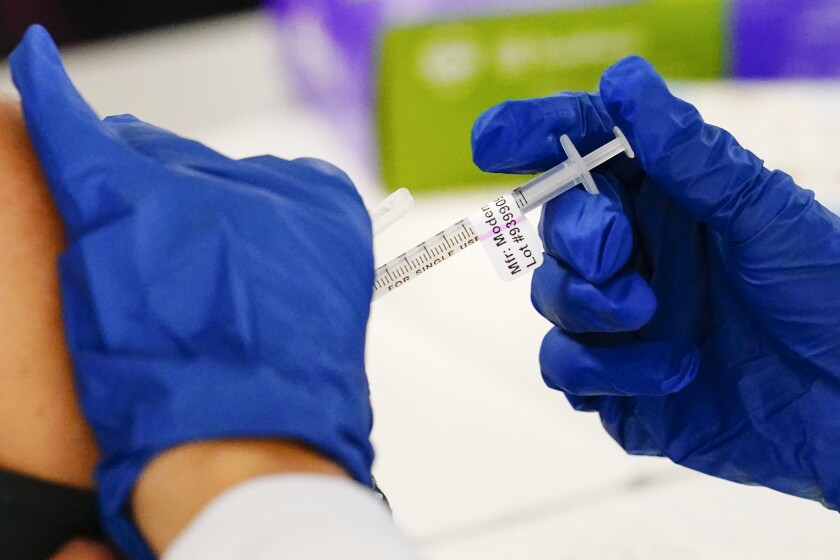 FILE - A health worker administers a dose of a Moderna COVID-19 vaccine during a vaccination clinic in Norristown, Pa. on Dec. 7, 2021. In a reversal for President Joe Biden, a federal appeals court in New Orleans on Monday, June 27, 2022, agreed to reconsider its own April ruling that allowed the administration to require federal employees to be vaccinated against COVID-19. (AP Photo/Matt Rourke, File)