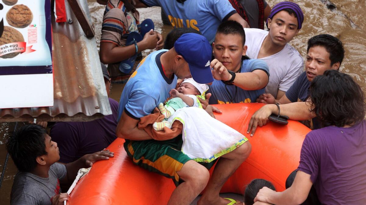 Police evacuate a baby in Cagayan City on Friday, Dec. 22, after the Cagayan River swelled from heavy rains brought on by Tropical Storm Tembin.