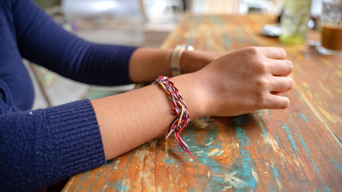 A girl at a cafe wears a braided bracelet.