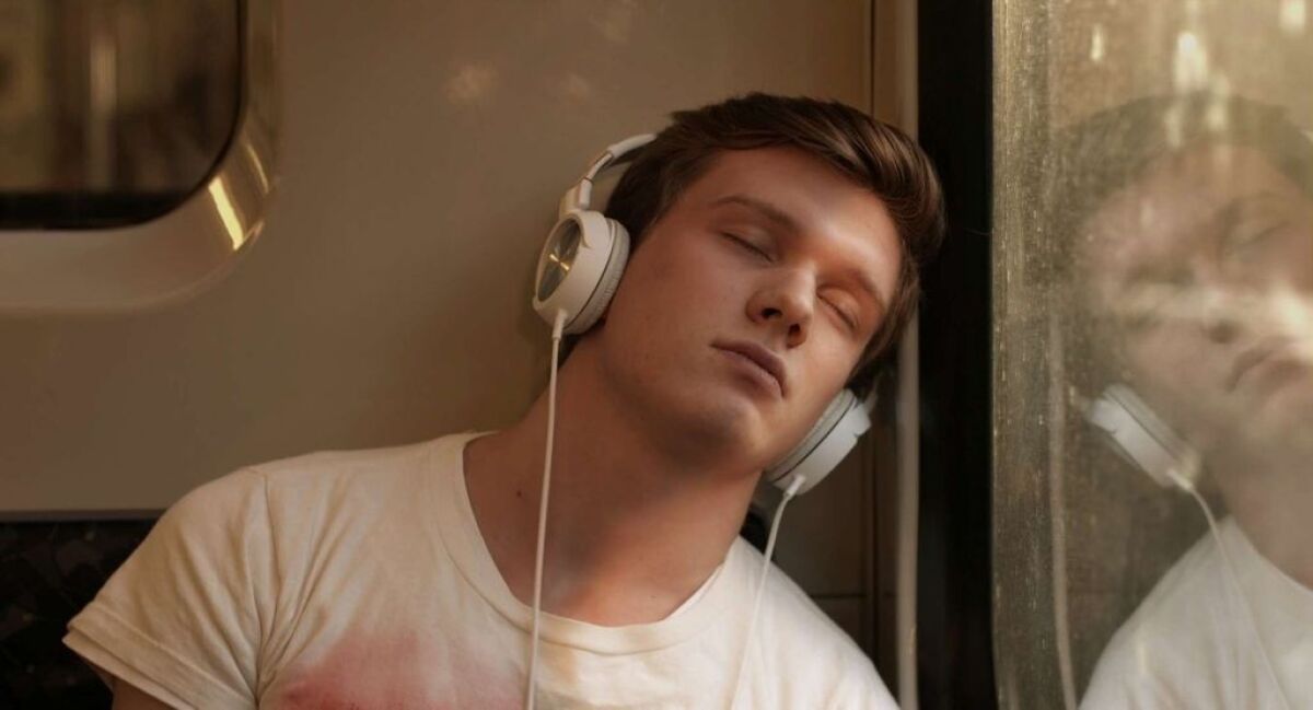 A young man with his eyes closed listening to headphones