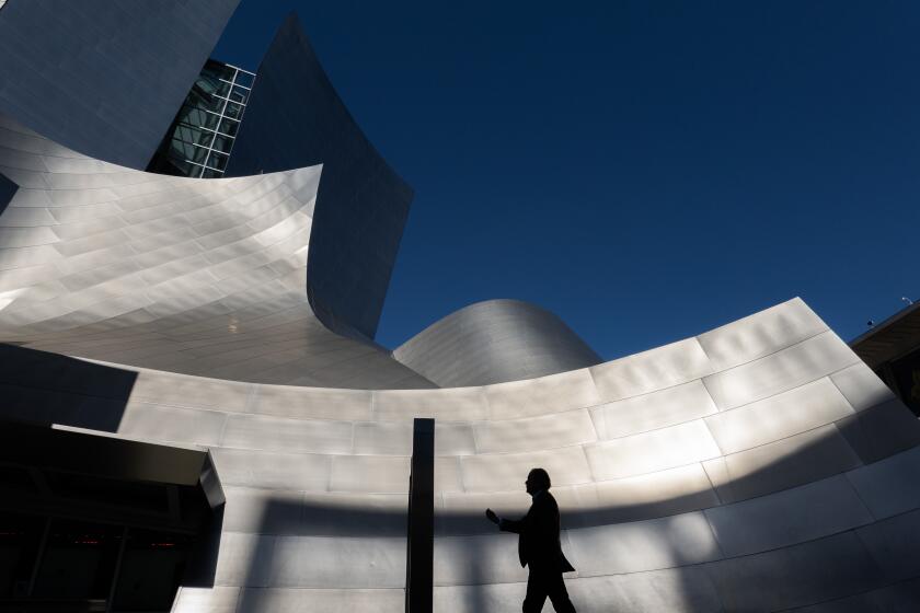 LOS ANGELES, CA- APRIL 06: A pedestrian walks past Walt Disney Concert Hall on a sunny, spring morning on Saturday, April 6, 2024 in Los Angeles, CA. More sunshine and warmer temperatures are expected in the coming days. (Myung J. Chun / Los Angeles Times)