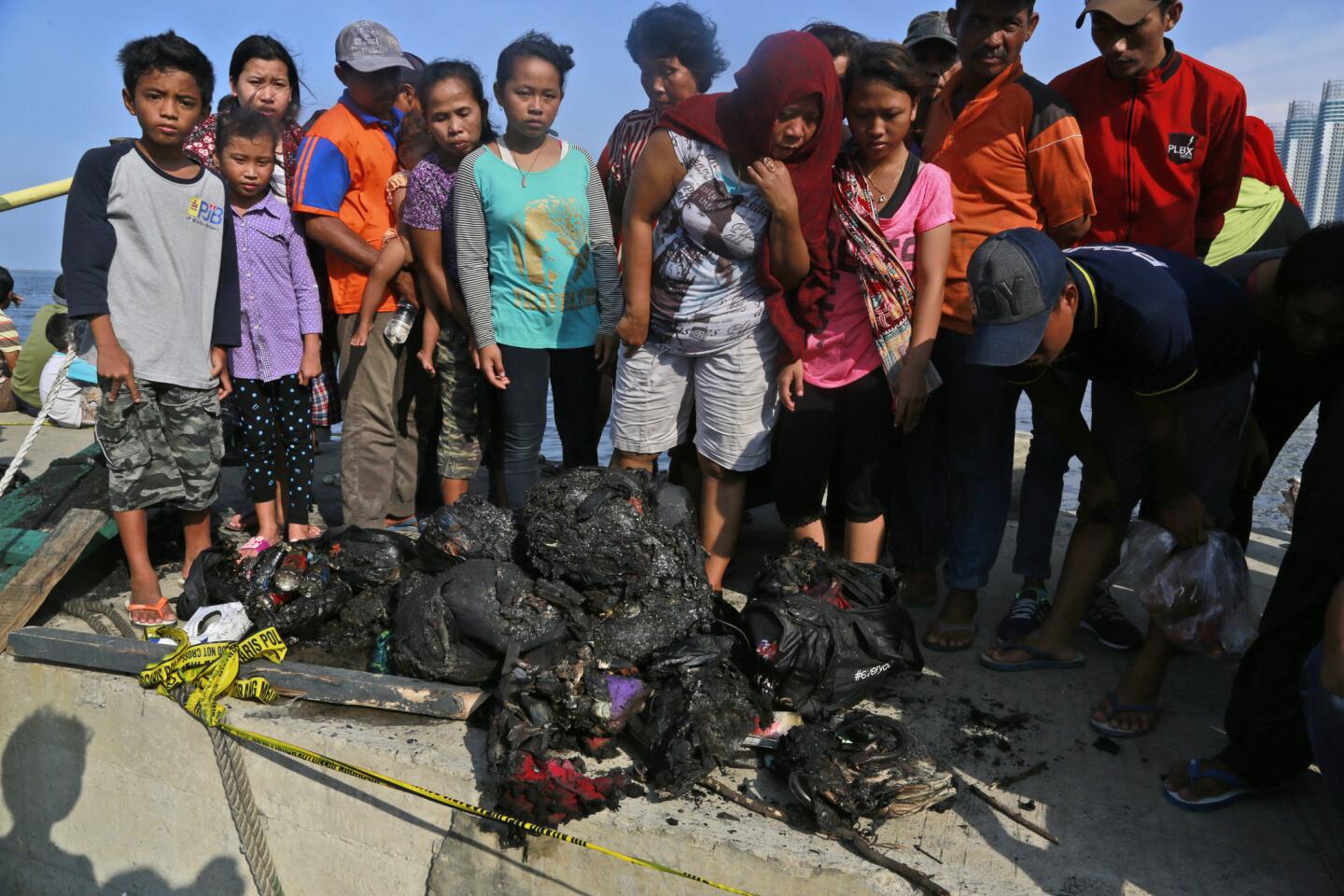 People inspect the charred personal belongings of passengers aboard the ferry that caught fire off Jakarta, Indonesia.