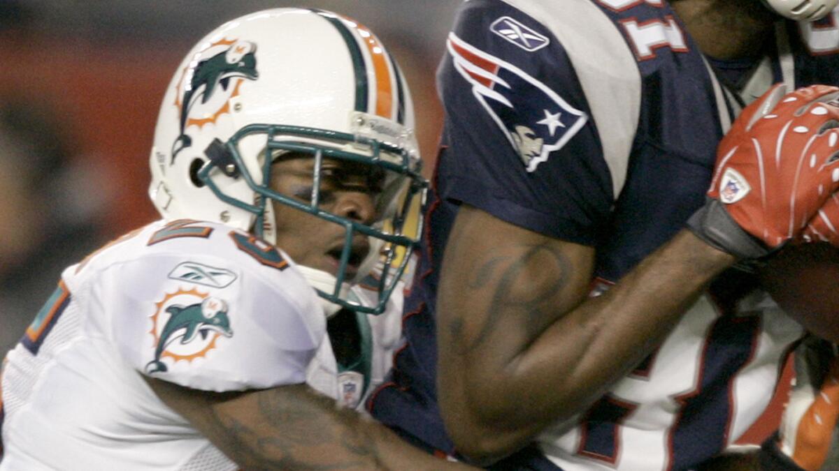 Miami Dolphins cornerback Will Allen, left, grabs New England's Randy Moss as the Patriots wide receiver catches a touchdown pass during a game in December 2007.