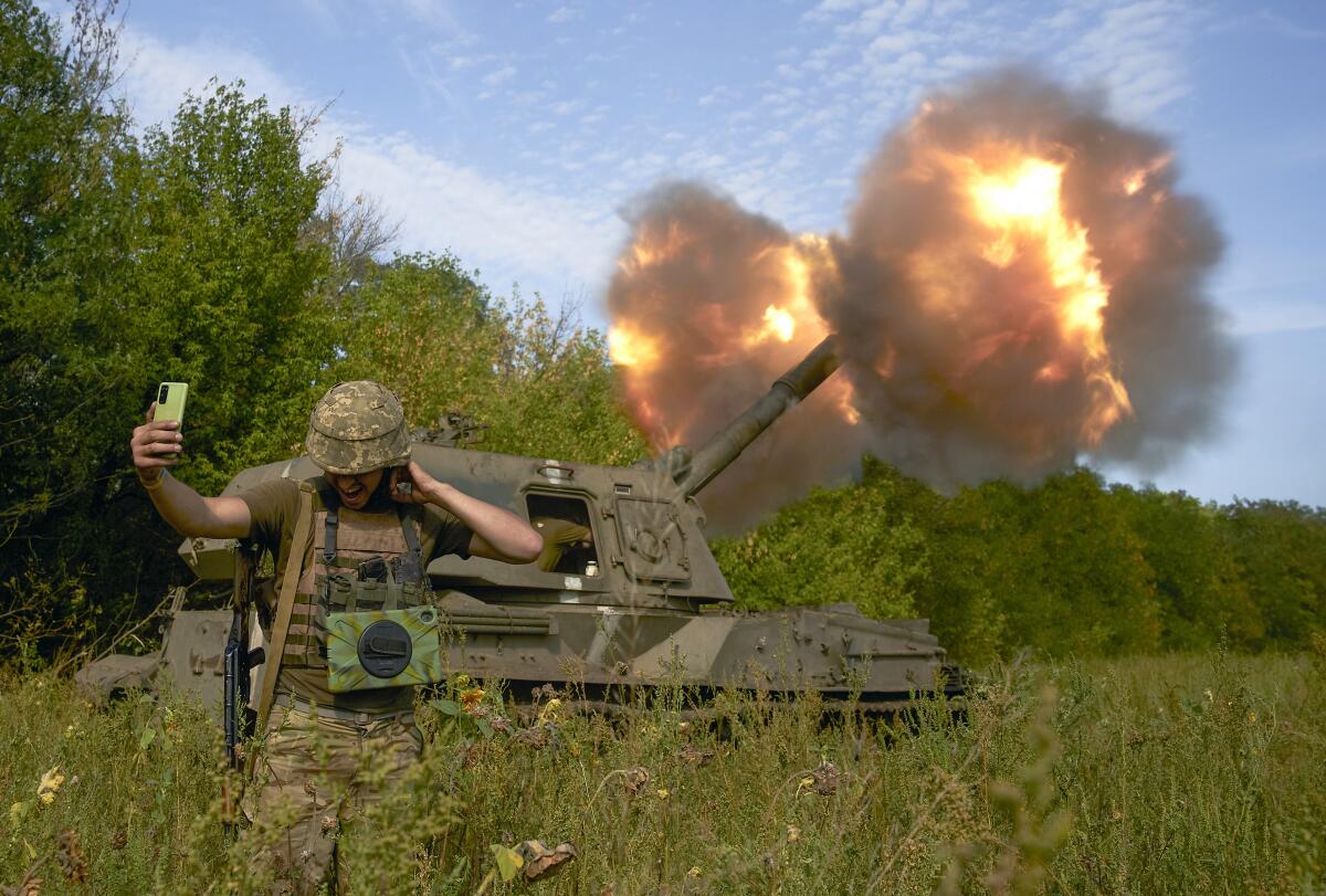 Un soldado ucraniano se toma una selfie mientras un sistema de artillería dispara un proyectil 