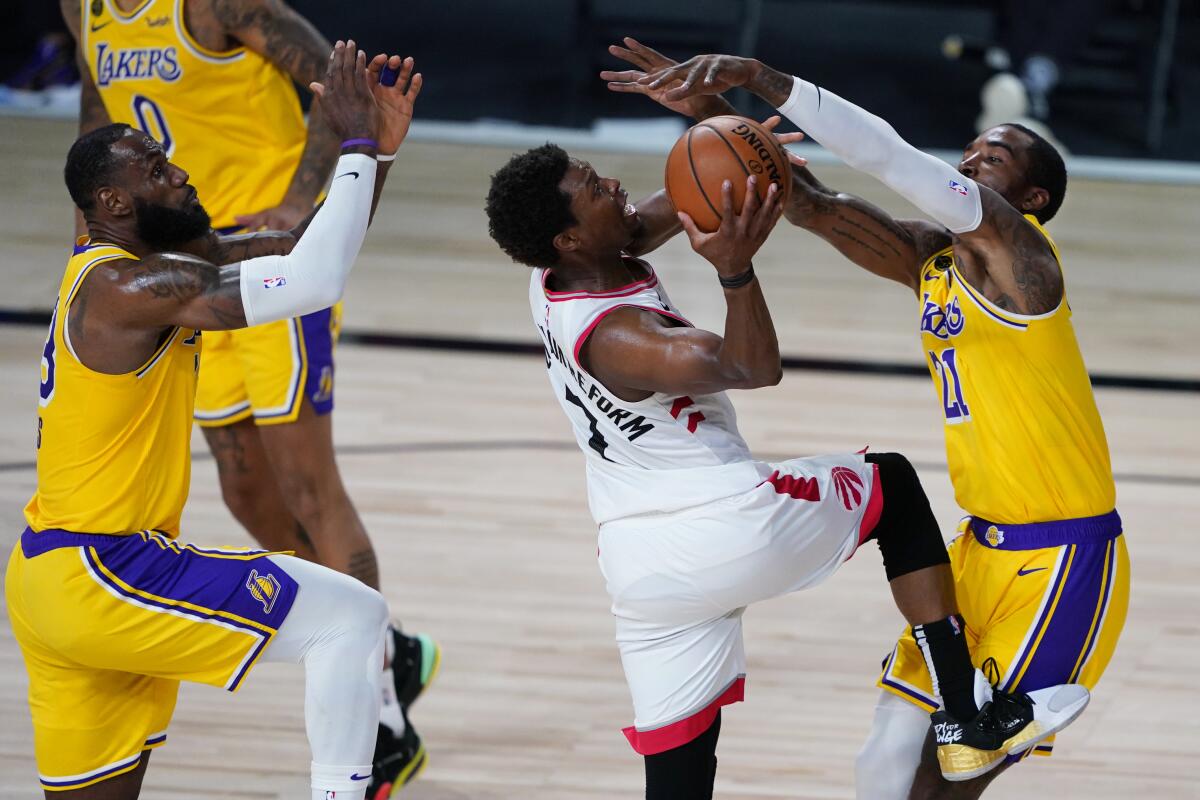 Lakers' LeBron James, left, and JR Smith, right, guard Toronto Raptors' Kyle Lowry during the second half on Saturday.