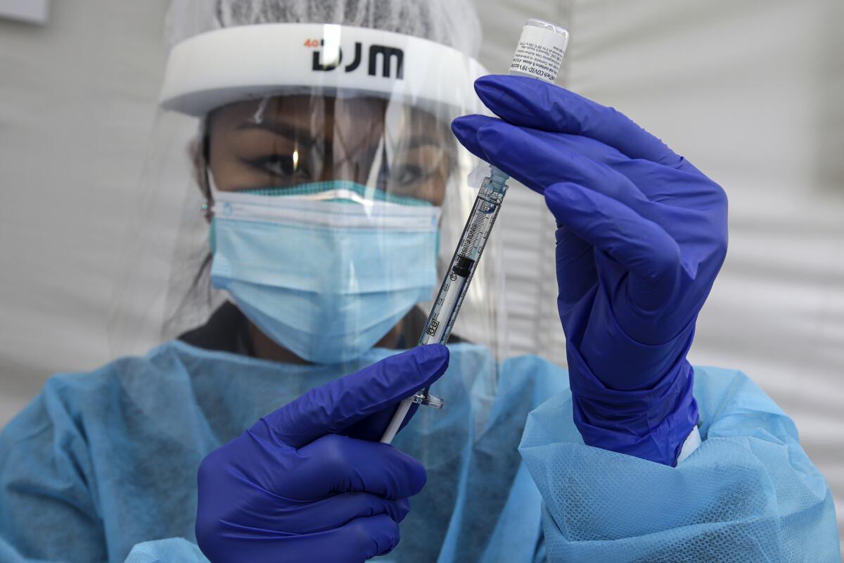 Nurse Cherry Costales prepares to administer COVID-19 vaccine at St. John's Well Child & Family Center in Los Angeles.