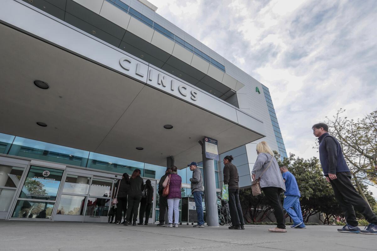 People stand in line outside a hospital clinic in Los Angeles
