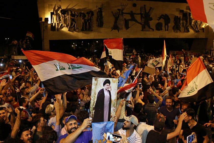 Followers of Shiite cleric Muqtada al-Sadr, displayed on the poster, celebrate in Tahrir Square, Baghdad, Iraq, early Monday, May 14, 2018. The political coalition of influential Shiite cleric Muqtada al-Sadr took an early lead in Iraq's national elections in partial returns announced late Sunday by the Iraqi electoral commission. (AP Photo/Karim Kadim)