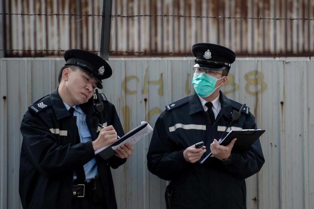 Two policemen take notes Jan. 28, 2014, near a wholesale market where infected poultry imported from mainland China was discovered in Hong Kong. Hong Kong is among the places that have been affected by the H7N9 bird flu virus, which has been less deadly than the SARS epidemic.