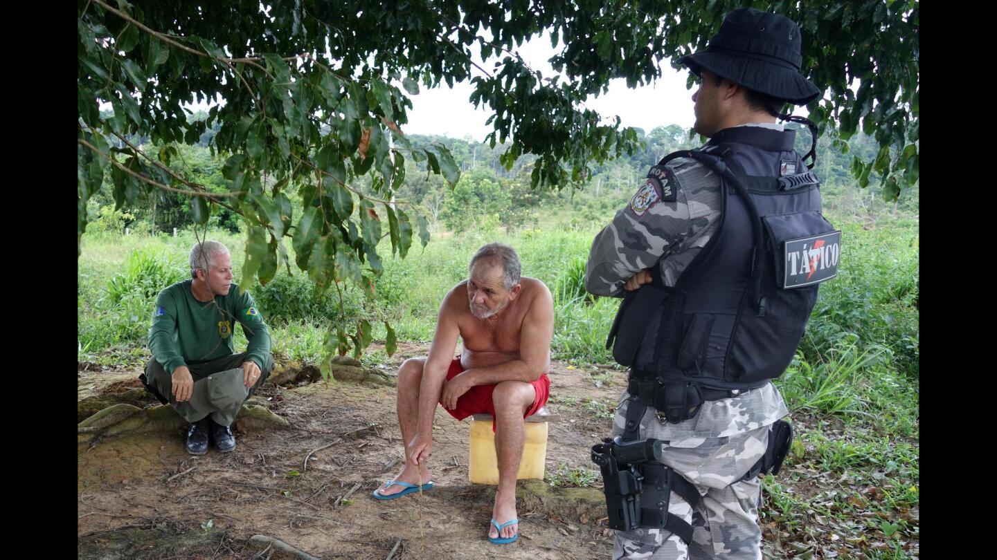An officer of the Brazilian Institute of Environment and Renewable Natural Resources questions a man found living near a recent deforestation site.