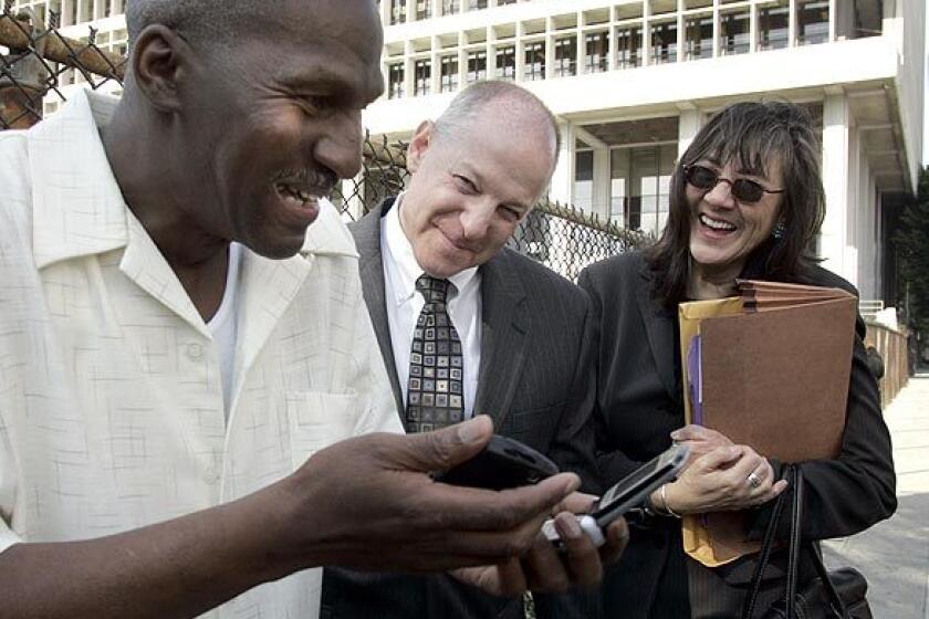 Willie Earl Green, left, marvels at a couple of cell phones with his attorneys Peter Camiel and Verna Wefald at his side.