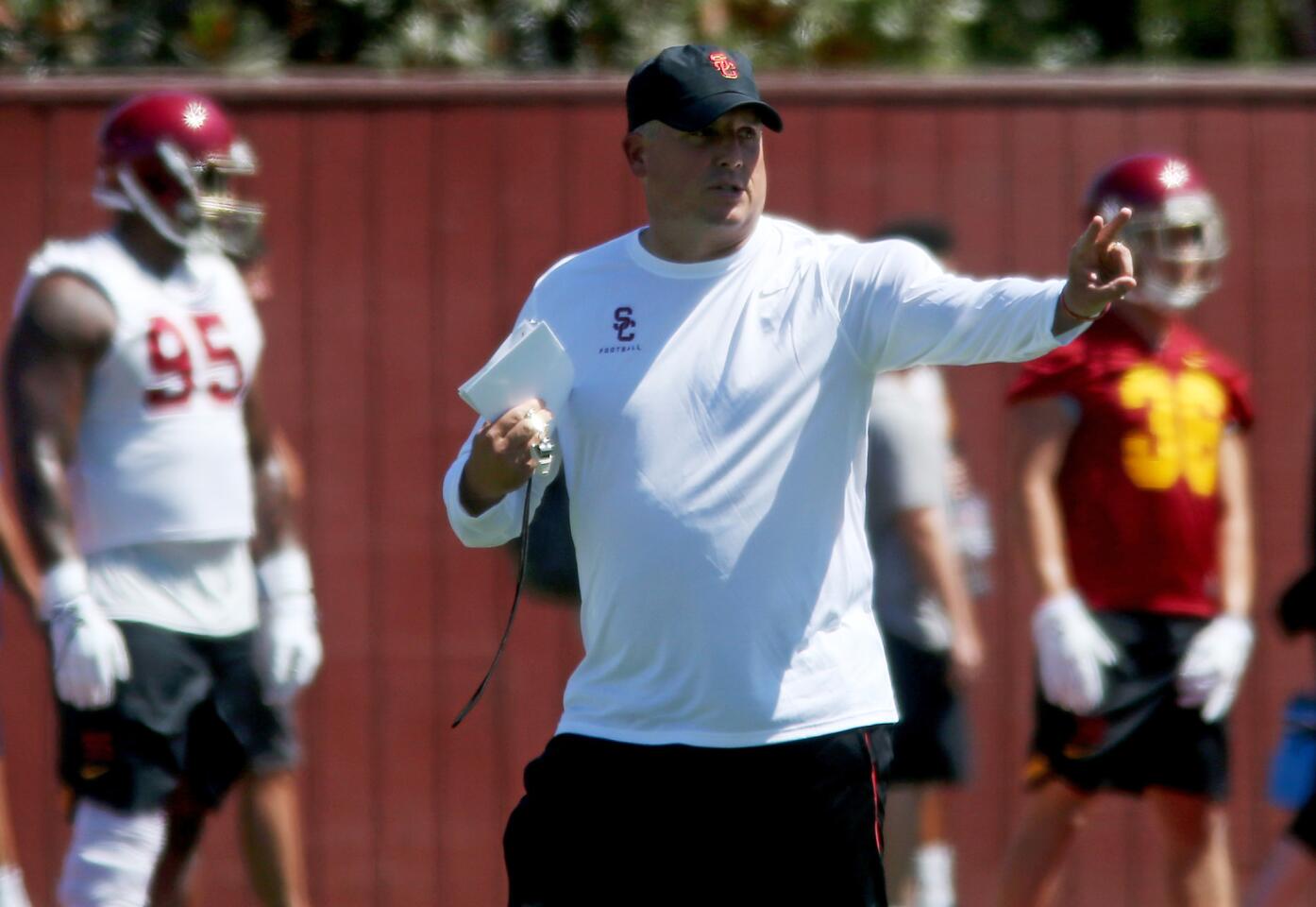 USC coach Clay Helton guides players through a workout during the summer camp opener.