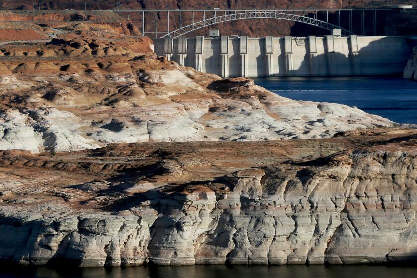 LAKE POWELL, ARIZ. - MAY 16, 2022. Water flows down the Colorado River at the Glen Canyon Dam near Page. White surfaces along the banks of the river and lake show previous water levels in the second largest reservoir in the U.S. It has been vastly reduced by relentless drought for more than a decade. In 2022 Lake Powell was at 3,522.24 feet above sea level with a capacity of about 22 percent. This is its lowest level since it was filled in 1963. (Luis Sinco / Los Angeles Times)