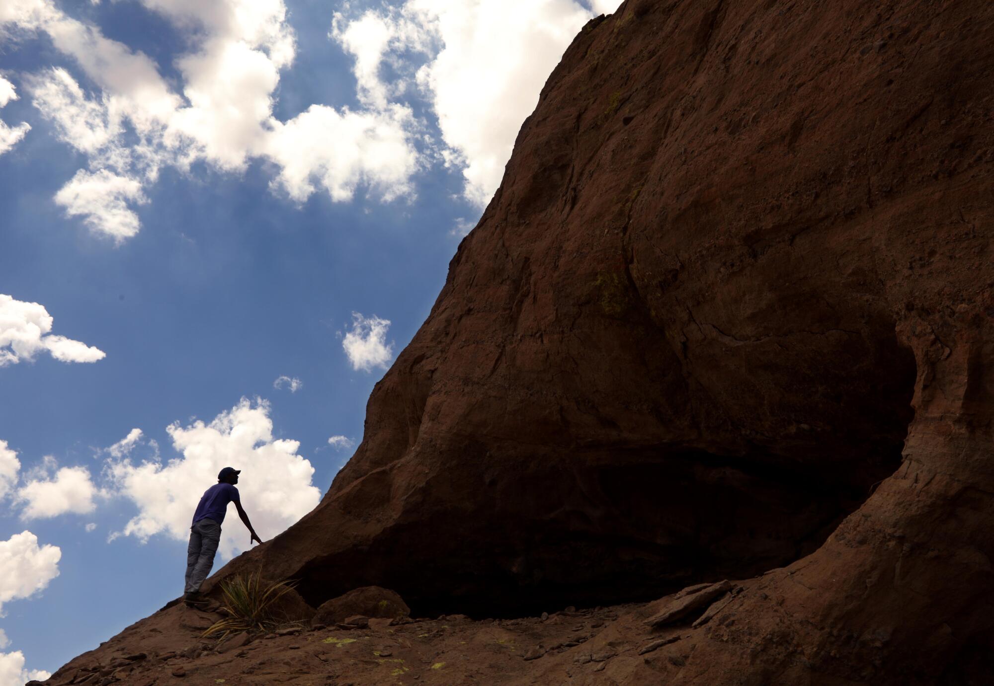A visitor silhouetted against the sky by a rock shelf