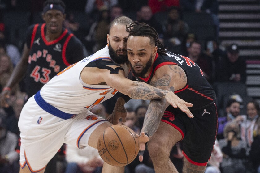 Toronto Raptors' Gary Trent Jr., right, and New York Knicks' Evan Fournier chase the ball during the first half of an NBA basketball game Friday, Dec. 10, 2021, in Toronto. (Chris Young/The Canadian Press via AP)