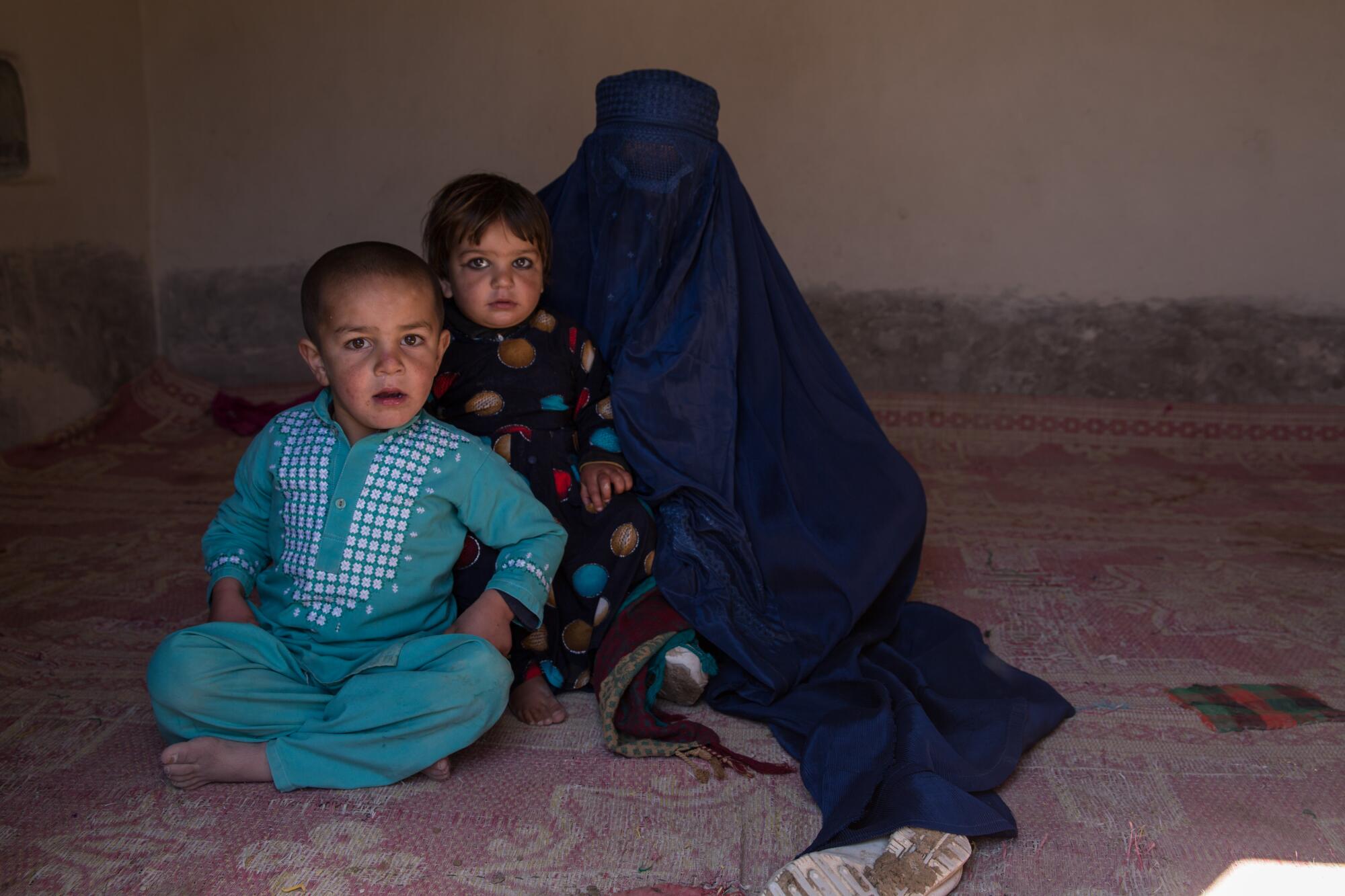 Maleika, 20, sits with two of her children. The Afghan woman, who asked not to show her face, says the Taliban “murdered my husband. They have no sympathy.”