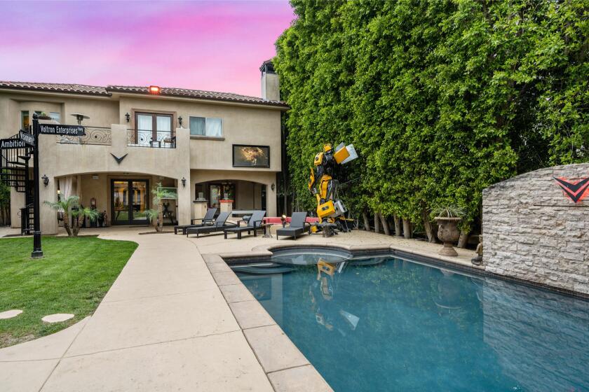 The Mediterranean-style property includes a backyard with a movie screen, swimming pool, street sign and giant Transformers replica.
