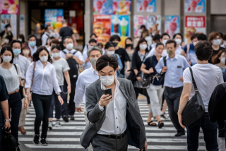 TOKYO, JAPAN - AUGUST 05: A man wearing a face mask cross a street as he checks.