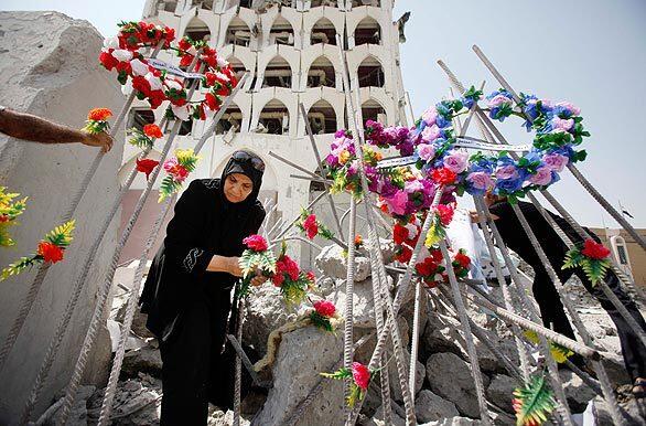 A woman places flowers in rubble in front of the Iraqi foreign ministry building a week after twin truck bombs targeted it and the finance ministry building, killing at least 101 people.