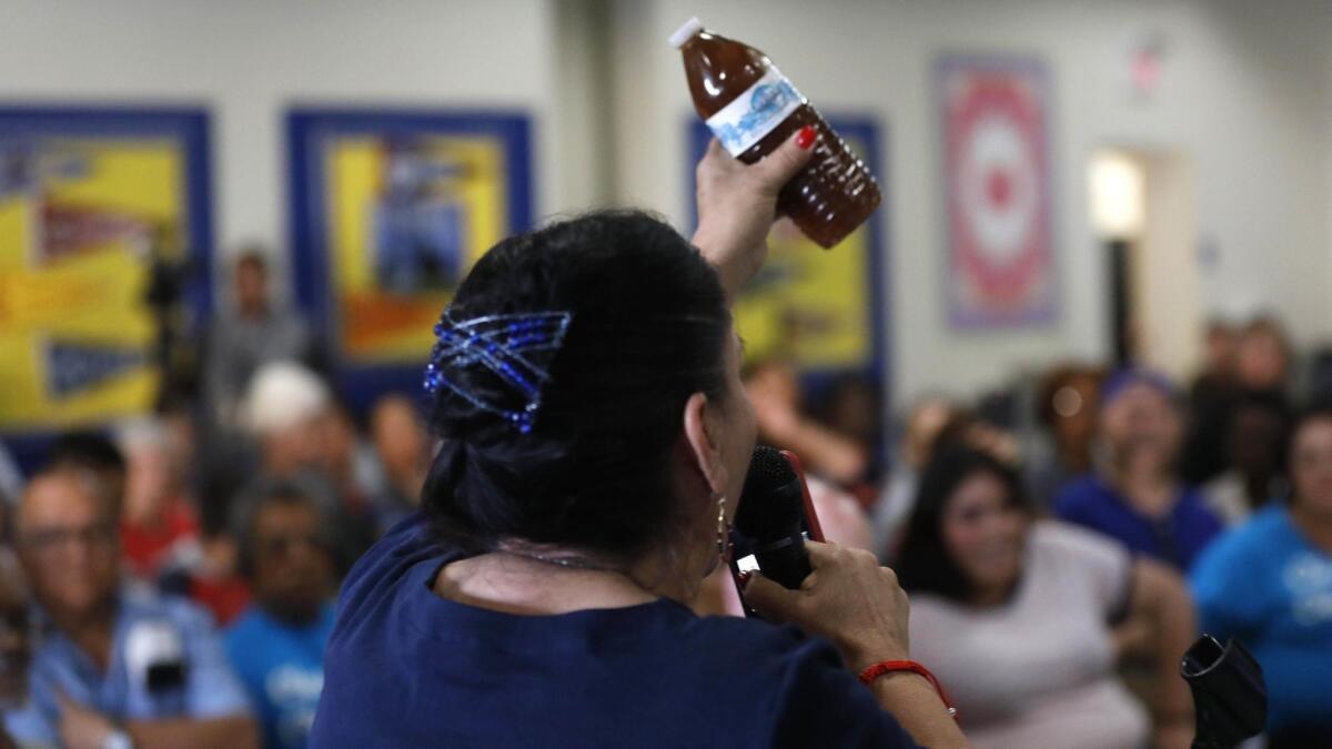 During Monday's town hall, Compton resident Maria Villarreal holds up a bottle containing brown water that she said came from the tap in her home.